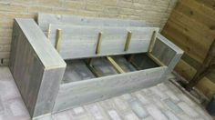 an unfinished bed frame sitting on top of a brick floor