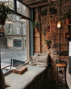 a window with some plants hanging from it's sides and a table in front of it