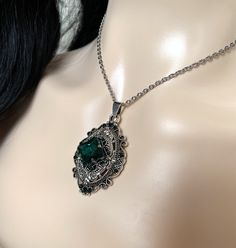 "This richly detailed antiqued silver plated filigree pendant, is adorned with dazzling EMERALD GREEN glass rhinestones that perfectly accentuate a larger jewel in the center. Pendant measures 2 1/4\" tall (including the bail) and 1 1/4\" wide. It is worn on a cable chain in your choice of length and fastens with a lobster clasp. Listing is for necklace ONLY. Matching earrings are listed in our store. This is available in a variety of stone colors in our store, along with matching earrings. If y Gothic Green, Dark Green Jewelry Necklace, Cheap Green Vintage Necklace, Luxury Gothic Necklaces For Formal Occasions, Luxury Victorian Green Jewelry, Emerald Green Vintage Necklace, Slytherin Necklace, Victorian Green Dangle Jewelry, Medieval Jewelry Emerald