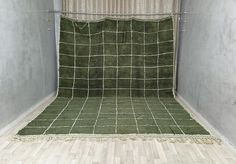 an empty room with a green rug on the floor and a curtain in the corner