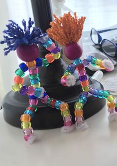 two vases with colorful beads are sitting on a table next to a pair of eyeglasses