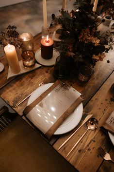 a wooden table topped with plates and candles