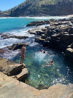 people are swimming in the ocean near rocks