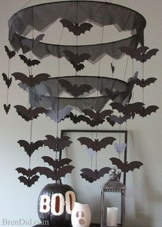 a table topped with halloween decorations and bats hanging from it's sides, on top of a shelf