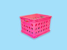 a pink plastic crate with holes on the sides and bottom, against a blue background