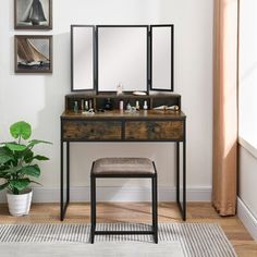 a dressing table with mirror and stool next to a potted plant