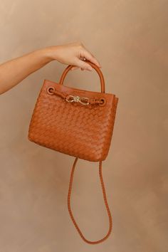 Meet our Blakely Light Brown Braided Purse, a fusion of style and functionality designed to elevate your everyday look. Crafted with a light brown faux-leather woven body, this purse exudes understated elegance. The small handle and braided crossbody strap offer versatility, allowing you to carry it with ease and style. Accentuating its charm is a sophisticated gold detail on the front, adding a touch of luxe to your ensemble. The magnetic closure ensures quick access to your essentials while ke Travel Dress, Leather Weaving, Jumpsuit Shorts Rompers, Understated Elegance, Romper Pants, Gold Details, Shoe Sale, Unisex Style, Crossbody Strap