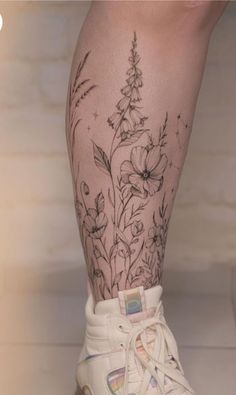 a tattoo on the leg of a woman with flowers and butterflies around her ankles,