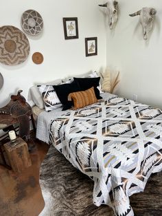 a bed with black and white bedspread sitting in a bedroom next to pictures on the wall