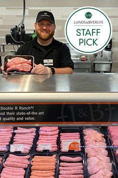 a man standing in front of a counter filled with pink and white donuts next to a sign that says staff pick