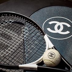 a tennis racket with a ball on it next to a pair of racquets