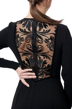 the back of a woman's black dress with an openwork design on it