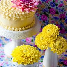 three cakes decorated with yellow and pink flowers on top of a table covered in floral fabric