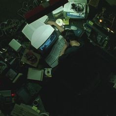 a person sitting in front of a laptop computer on top of a desk covered in clutter