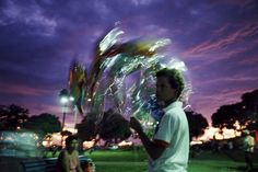 a man standing next to a woman holding a bunch of flowers in front of a purple sky