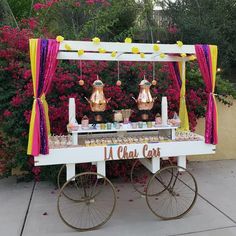 an outdoor dessert cart with pink and yellow decorations