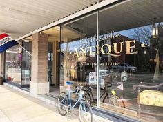 a bicycle is parked in front of an antique store with its glass doors and windows