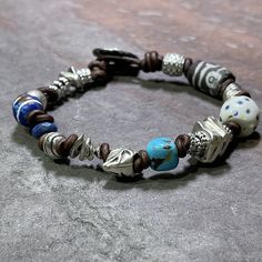 "Reflecting on my travels and experiences, and the people I have met and the places I have lived and seen made me want to create something that represented a mix of those.  So I expanded a bit on my Chunky Monkey design and added some antique genuine trade beads, a single genuine turquoise nugget, and an array of mixed shapes of handmade pewter in fun organic shapes and sizes.  All on dark antique brown leather finished with an easy pewter button.   Fits 6.5\" - 7\" wrist.  Need a different size?  Message me and I'll be happy to help. *Due to the nature of the handmade trade beads your bracelet may not look exactly like the one shown, but your bracelet will contain the same mix of beads as shown.  If you would like to see your bracelet prior to shipping please leave me a note in the notes Bohemian Brown Bracelets With Silver Beads, Handmade Spiritual Leather Bracelet, Handmade Spiritual Leather Bracelet For Everyday, Bohemian Silver Beaded Bracelets For Everyday, Nickel-free Bohemian Beaded Bracelets For Healing, Handmade Spiritual Leather Bracelet With Round Beads, Bohemian Silver Beads Bracelets For Healing, Bohemian Silver Beads Bracelet For Healing, Silver Bohemian Beaded Bracelets For Everyday