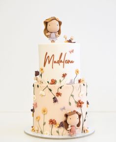 a three tiered cake decorated with flowers and an animal figurine on top