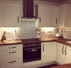 a kitchen with white cabinets and wooden counter tops