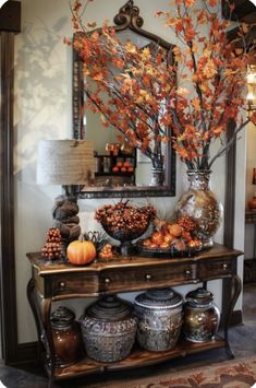 a table topped with lots of vases filled with flowers and autumn leaves in front of a mirror