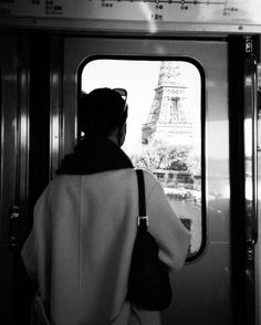 a woman is looking out the window of a train at the eiffel tower