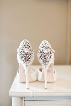 a pair of white high heeled shoes sitting on top of a table next to a dresser