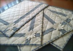 three quilted placemats with blue and white flowers on them sitting on a table