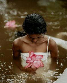 a woman in the water holding a pink flower