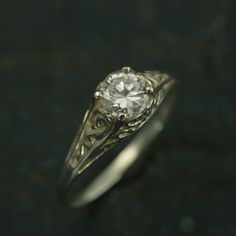 a close up view of a ring with a diamond in the center on a black surface