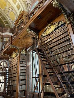 an old library with many bookshelves and wooden stairs leading up to the second floor