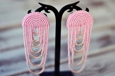 two pairs of pink beaded earrings on a black stand