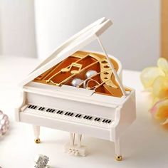 a miniature white piano sitting on top of a table next to a vase with flowers