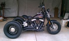 a black motorcycle parked in a garage next to a white tarp covered wall and floor