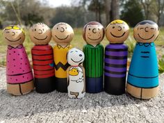 a group of wooden peg dolls sitting on top of a cement slab in the grass