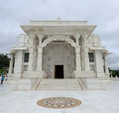 a large white building with steps leading up to the entrance and some people walking around