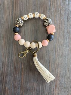 a close up of a tasseled bracelet on a wooden surface with an animal print charm