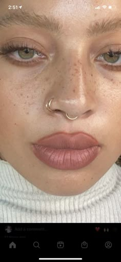 a woman with freckles and piercings on her nose