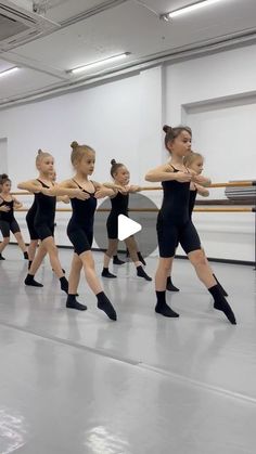 a group of young women in black leotards are practicing ballet moves on the floor