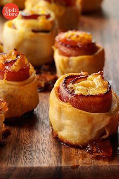 small pastries are lined up on a cutting board with bacon and cheese in the middle