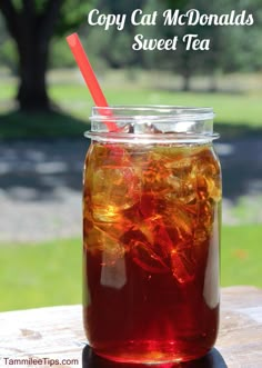 a jar filled with liquid sitting on top of a wooden table next to a green field