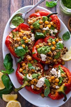 some stuffed peppers are on a plate with lemon wedges and garnishes