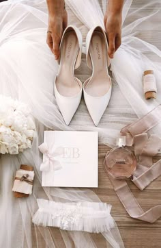 a bride's wedding shoes and accessories laid out on the floor next to her bouquet