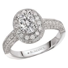 a white gold engagement ring with diamonds on the band and an oval center stone surrounded by round