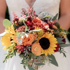 a bride holding a bouquet of sunflowers and other flowers