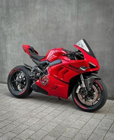 a red motorcycle parked next to a cement wall