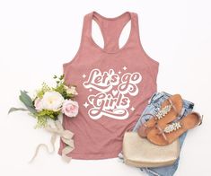 Looking for the perfect bachelorette party shirt? Look no further than our lets go girls tank top! This fun and stylish shirt is perfect for any country music lover. Our tank features a cute let's go girls graphic on the front, and is made from soft and comfortable cotton. It's also great for any bridal party - make sure to get one for your bride-to-be! Finally, if you're looking for a unique gift for your girlfriend, then our lets go girls tank top is perfect! The solid color Unisex Tees are su Fitted Racerback T-shirt For Summer, Trendy Summer T-shirt For Bachelorette Party, Sleeveless Slogan Top For Spring, Spring Sleeveless Slogan Top, Summer Party Tank Top With Graphic Print, Graphic Print Tank Top For Summer Parties, Summer Party Tank Top With Crew Neck, Cute Summer Party Tank Top, Summer Slogan Tank Top