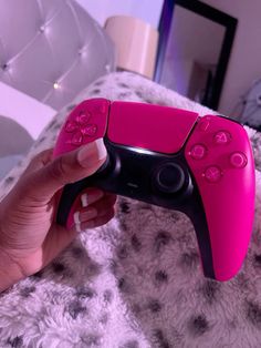 a person is holding a pink video game controller