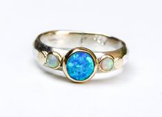 Recycled Silver and 14k Gold With blue and white Opal ring (The listing is only for the ring with the stone) If you want it with the secend ring: https://www.etsy.com/listing/155717400/gold-ring-wedding-bands-stackable-rings?ref=shop_home_active_52 You are looking at a beautiful HAND MADE silver and 14k gold ring with lovely blue opal. The opal stone is setting in 14k gold bazel. It is impressive, powerful and very beautiful ring. Size blue opal is 6mm White opal are 3 mm Custom rings are availa 14k Gold Opal Ring, Ring Wedding Set, Australian Opal Ring, Blue Opal Ring, October Birthstone Rings, White Opal Ring, Handmade Engagement Rings, Opal Ring Gold, Gold And Silver Rings