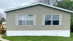 a mobile home sits on the grass in front of some trees